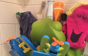 Bath toys, kids' wash clothes, and shampoo bottles on the shelf of a Boon Frog toy pod