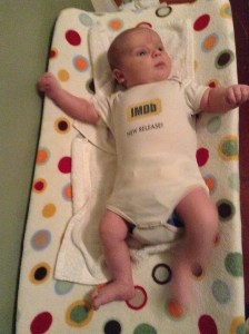 An awake baby lays on a changing pad with a polka dot cover