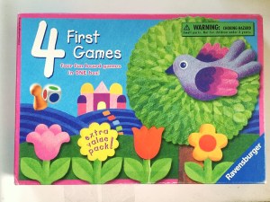Four First Games box lid from Ravensburger with four flowers, a bird, a tree, a colored die, and one playing piece shown on the cover of the box