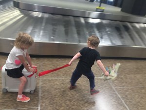 One child pulling another riding on the JetKids BedBox ride on suitcase