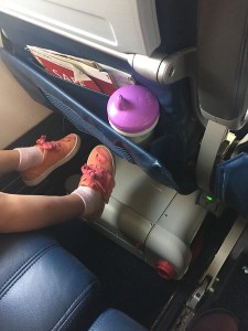 JetKids BedBox shown stored underneath a seat on an airplane