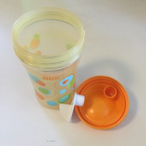 An open Nuk ultimate hard spout sippy cup showing the three parts: cup, lid, and valve