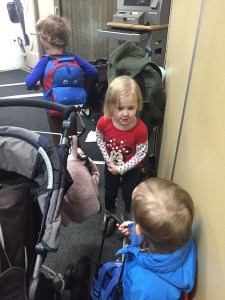 Three kids carrying small suitcases on a jetway