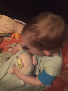 Toddler snuggling a Baby Stella doll by Manhattan Toy