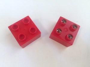Light Stax plastic interconnecting building block next to a Lego Duplo block