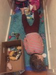 Six year old passed out on rug in hall among scattered toys