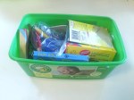 Child art supplies like crayons stored in am empty disposable wipes container
