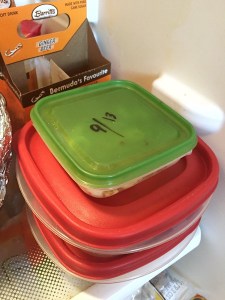 Food storage containers stacked in fridge with date written in dry erase marker