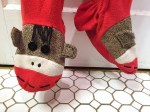 Close up of sock monkey decoration on feet of adult footie pajamas by Nick and Nore