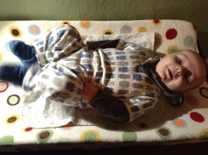 Baby laying on changing pad liner on top of contoured changing pad