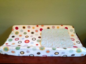 Changing pad liner on top of contoured changing pad on dresser