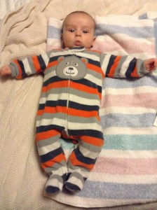 Infant in striped pajamas laying on striped towel