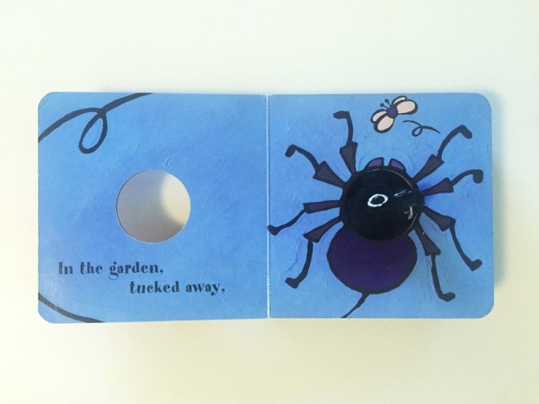 Little Spider finger puppet board book open to blue page spread with hole for puppet