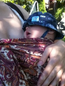 Infant napping in ring sling wearing blue sun hat