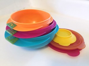 Sassy snack bowl 3 piece set shown stacked next to lids and suction cup base