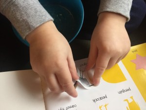 Child attaching sticker to activity book