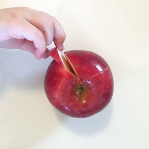 Toddler hand removing piece from sliced apple