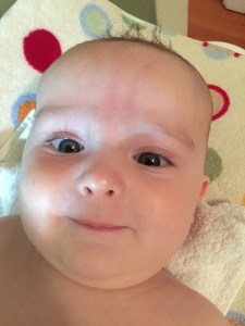 Infant smiling on polka dot changing pad cover