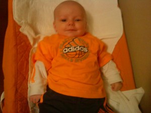 Infant laying on orange changing pad cover