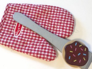 Oven mitt, wooden silver spatula and cookie with chocolate frosting and sprinkles from Melissa and Doug wooden slice and bake cookie set