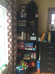 72 inch black bookshelf holding toys, games, and books