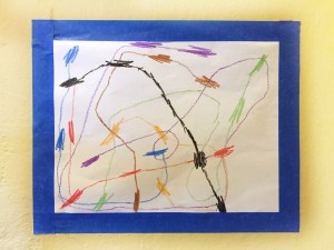 Child's artwork displayed on wall surrounded by blue painters tape