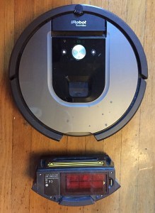 Roomab robotic vacuum with collection tray removed nearby