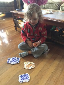 Three year old playing Slamwich card game on floor