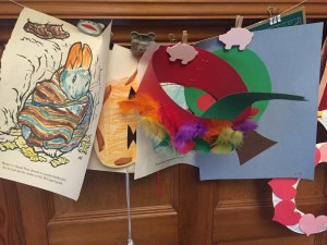 Coloring pages, hat, and glueing projects displayed on wall