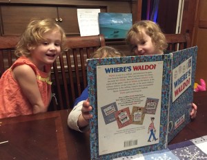 Three kids looking for Waldo in Where's Waldo book