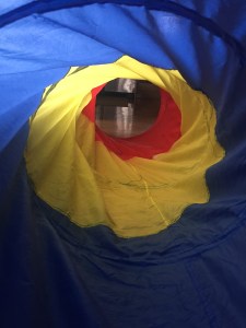 Inside a pop up tunnel for kids in blue yellow and red