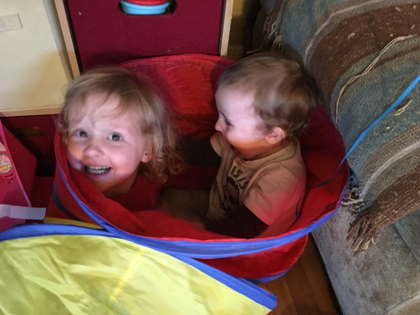 Two kids inside the pop up tunnel at the same side