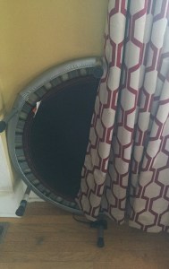 Trampoline stored upright partially hidden behind curtain