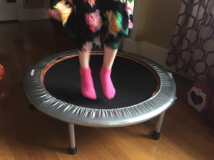 Child's feet in pink socks while jumping on exercise trampoline