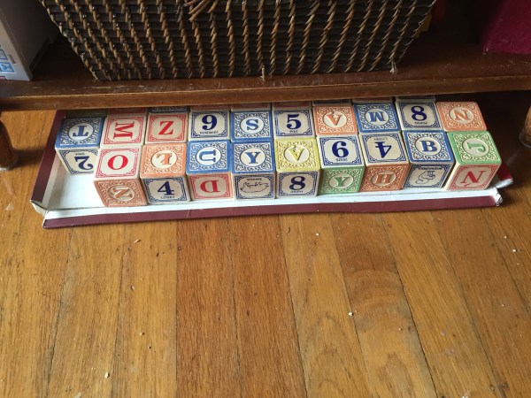 Uncle Goose blocks on cardboard tray tucked partially underneath coffee table