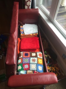 Homepop red faux leather storage bench shown open with blankets inside and bins of toys stored underneath