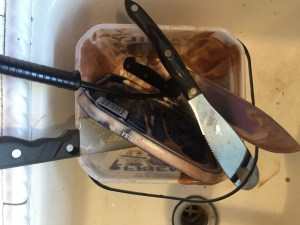 Dirty utensils covered in melted ice cream in sink