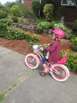 Child riding pink and white bike wearing hot pink wipeout helmet decorated with dry erase markers