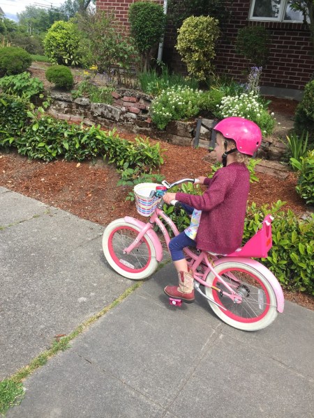 Child riding pink and white bike wearing hot pink wipeout helmet decorated with dry erase markers