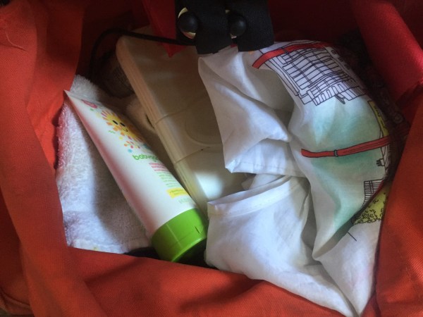 Sunscreen, cloth, wipes case, and bag stored underneath Bugaboo Frog stroller in orange