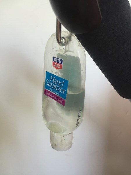 Hand sanitizer travel size bottle hanging from bag hook on stroller