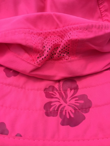 Purple flowers on pink sun hat appear in sunlight