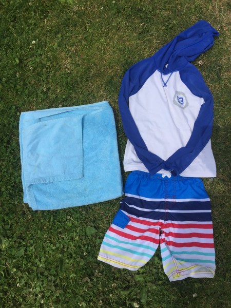 Towel, swim shirt, and swim trunks on grass
