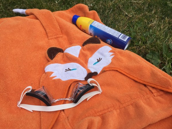 Hooded orange fox towel, spray sunscreen, and googles