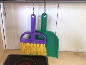 Schylling dust pan and hand broom hanging from kids IKEA play kitchen hooks