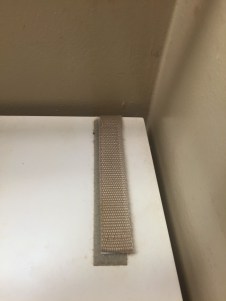 Furniture anchor installed on white bathroom cabinet with tan Velcro
