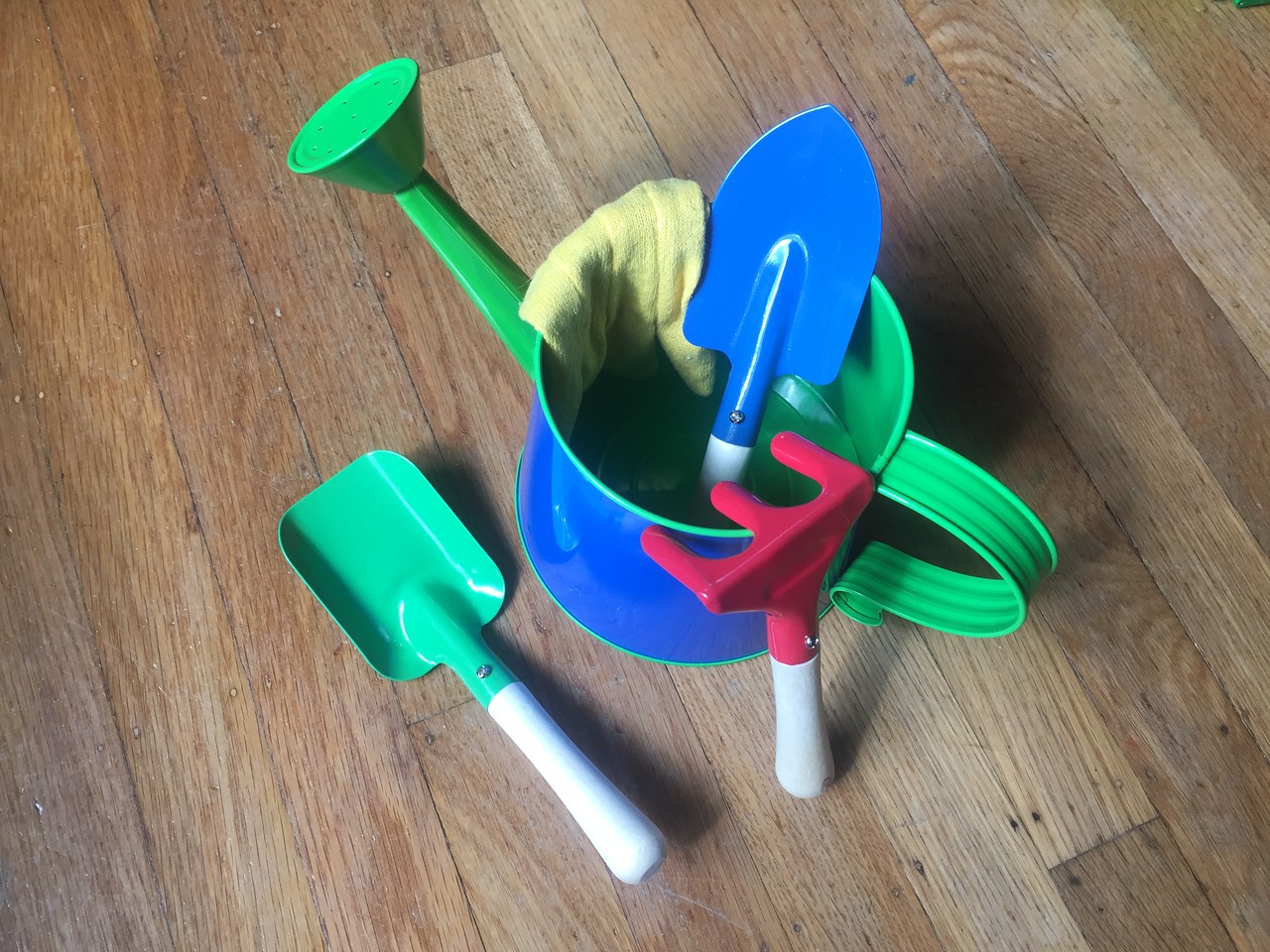 Toysmith kids small gardening tools set with blue watering can, green shovel, blue trowel, red rake, and yellow gloves