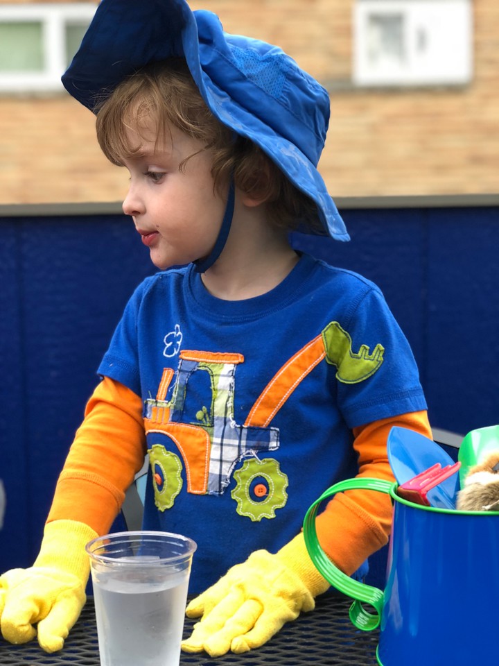 Child wearing yellow garden gloves at table