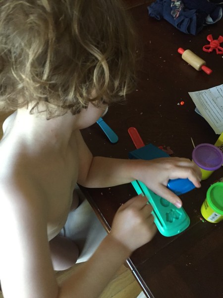 Child playing with Play-Doh fun factory on table