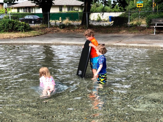 Two kids holding boogie body board in wading pool